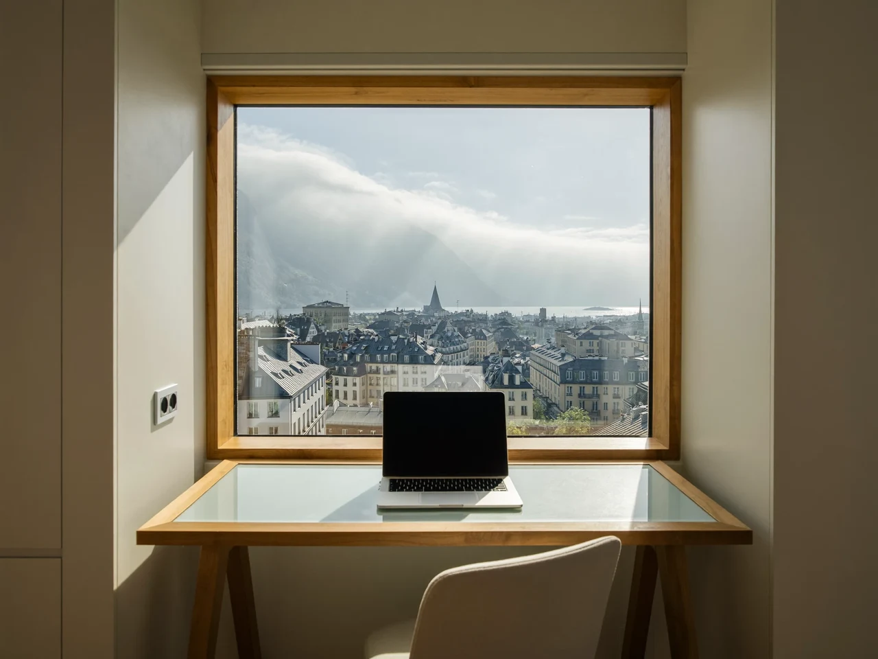 Sonnendurchfluteter Arbeitsplatz in einer Schweizer Stadtwohnung mit Laptop und Blick über Dächer