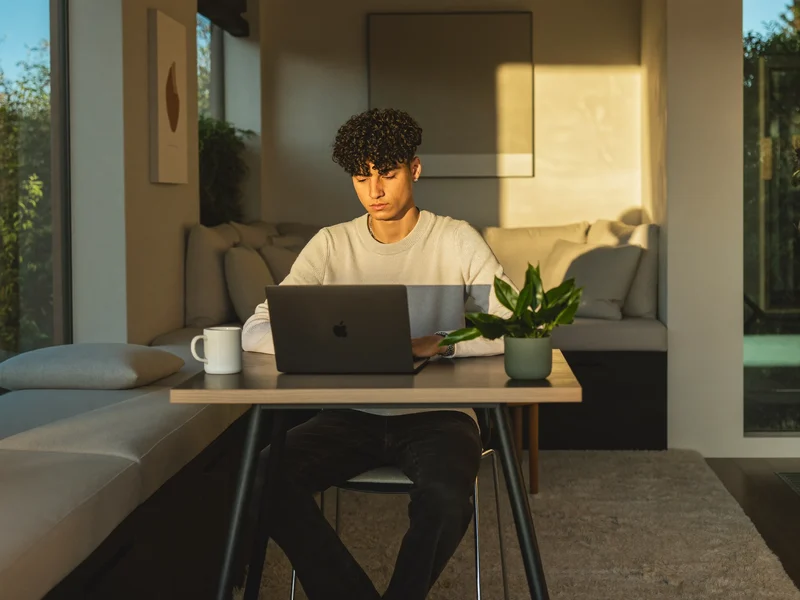 Lernende am Laptop in heller Leseecke mit Tasse und kleiner Pflanze